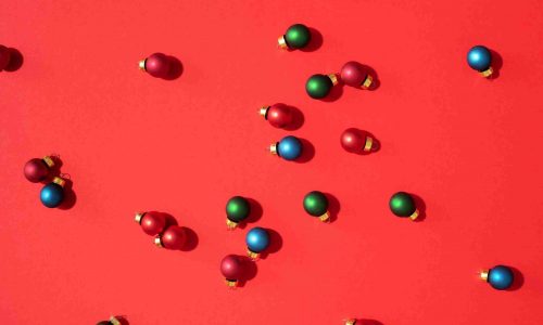 Christmas pattern made of colorful christmas baubles on red background. Flat lay, top view. New year concept.